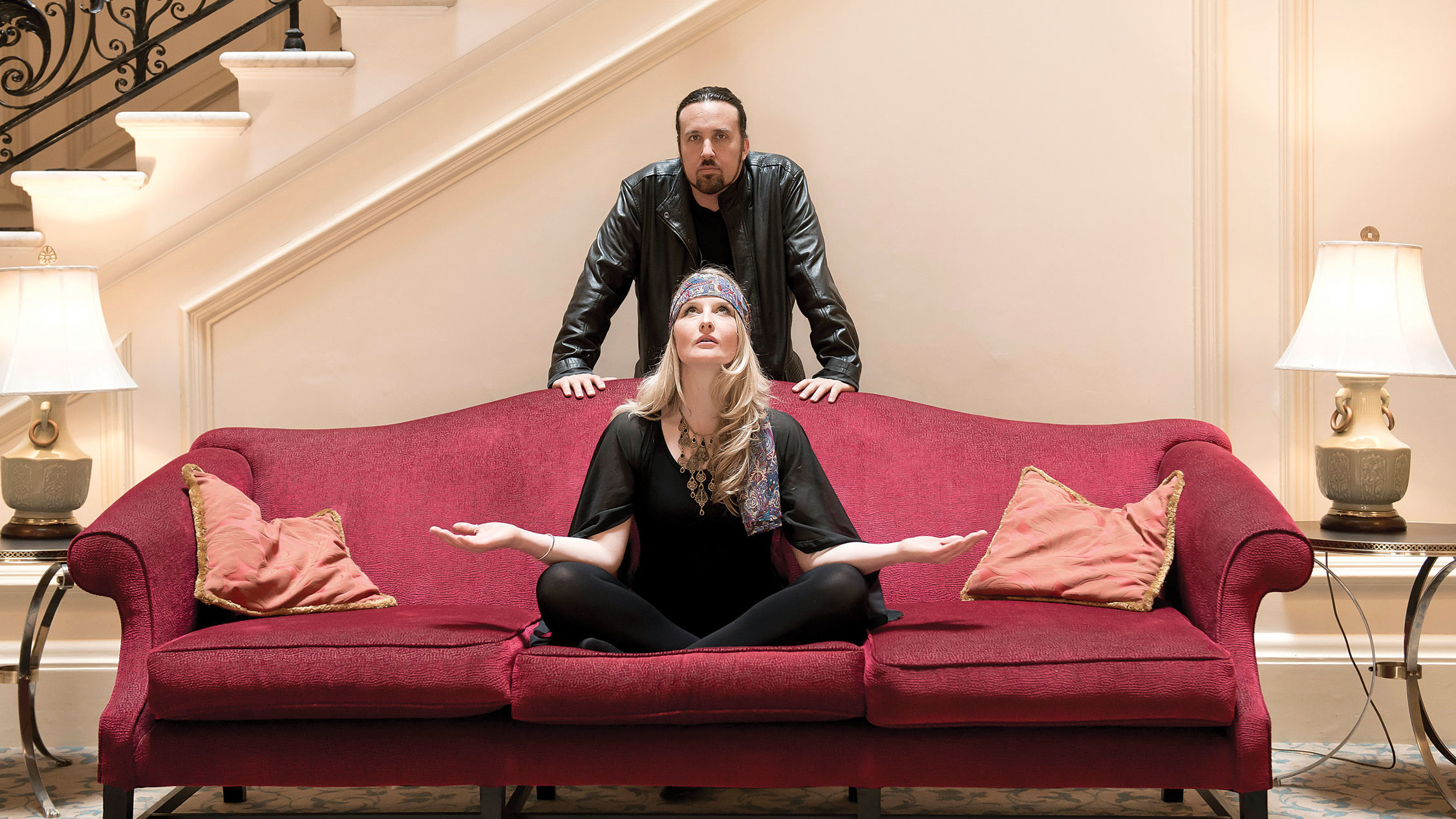 Mantra Vega&#039;s Heather Findlay and Dave Kerzner throwing yoga poses on a red sofa