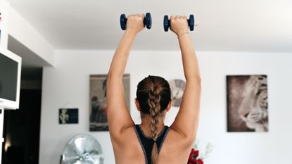 Woman holding dumbbells up and overhead