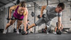 woman and man facing performing a renegade row wearing gym clothes, in a gym setting.