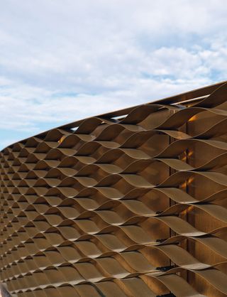 A honeycomb brass veil wraps a building in Switzerland