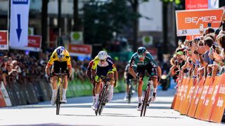 Wout van Aert of Belgium and two fellow riders race across the finish line at the Hamburg Cyclassics UCI World Tour event.