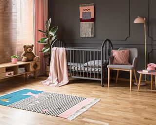 Dark gray nursery ideas, with a painted crib and blush pink soft furnishings.