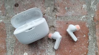 the jbl tune 230nc true wireless earbuds next to their charging case