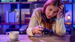 A female gamer looks frustrated sat at a desk