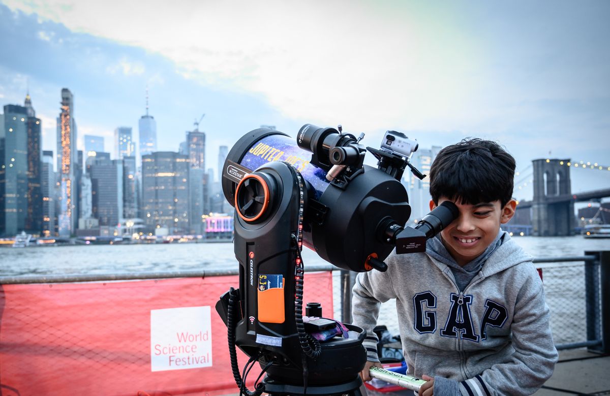 A child uses a telescope at the &quot;Saturday Night Lights&quot; event held at Brooklyn Bridge Park as part of the 2019 World Science Festival.