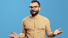 An irritated-looking man makes a gesture with his hands like, "What happened?" 