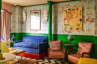 A colorful communal space with green panelled walls, floral wallpaper and colourful artwork on the walls