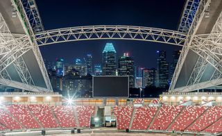 Night view of sports hub with red seating and city lights behind