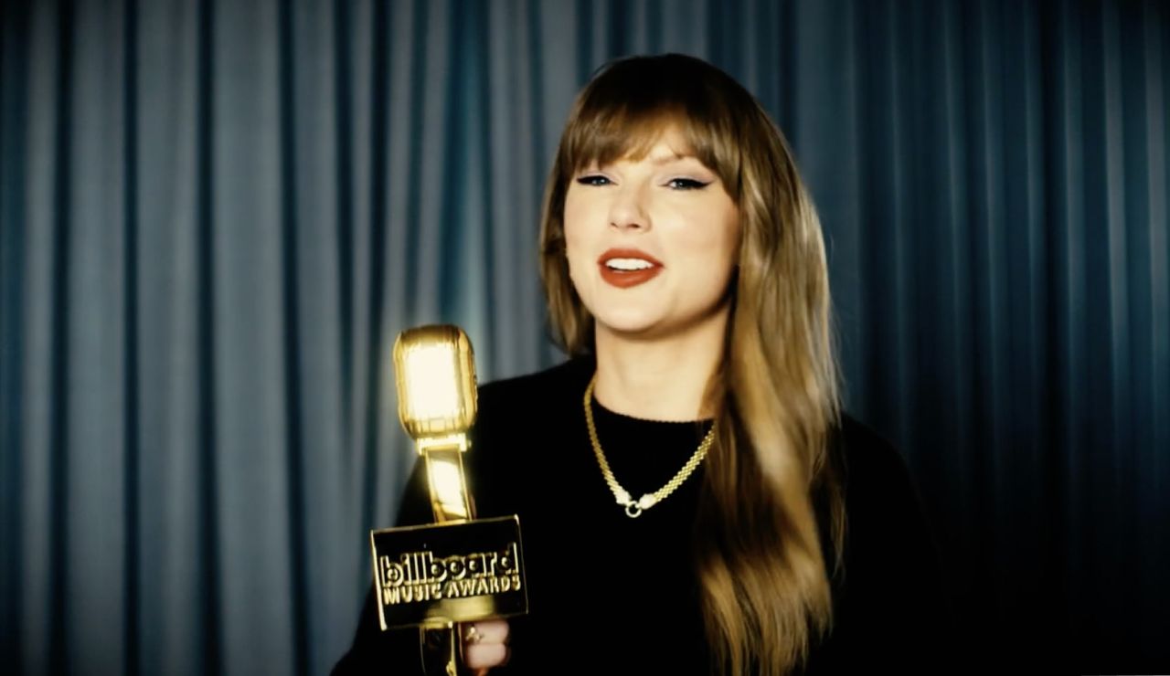 Taylor Swift tapes a video thanking fans for her Billboard music awards wearing a black sweater and a gold necklace from Effy jewelry