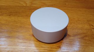 Surface Dial review; a small silver metal circular gadget on a wooden table
