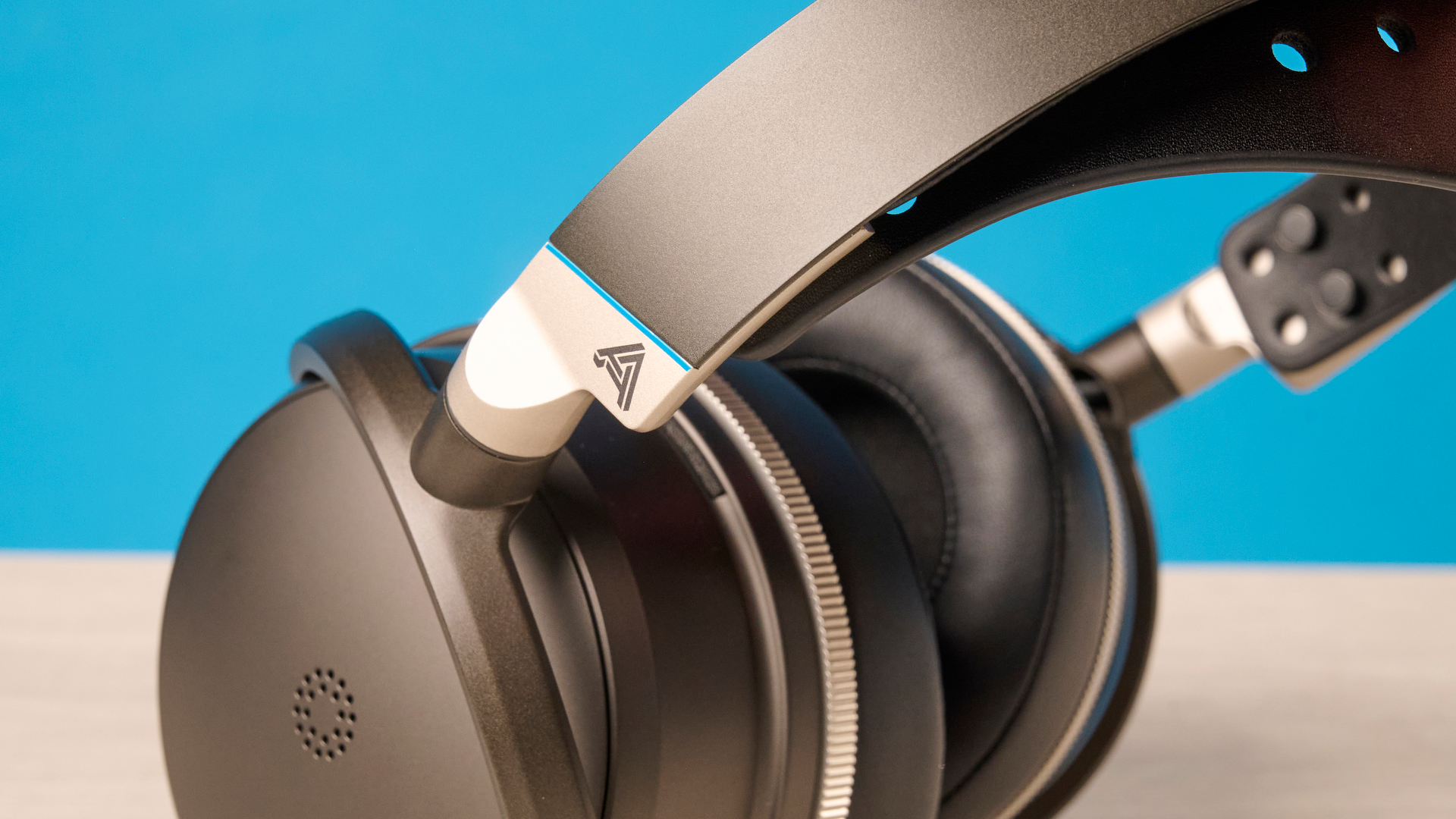 The Audeze Maxwell 2 ANC on a wooden desk with a blue background