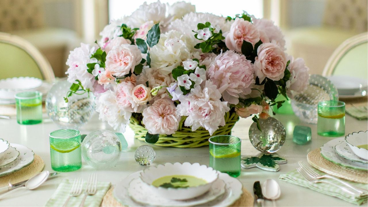 Spring table with large bouquet of roses and peonies, green glasses and white china plates