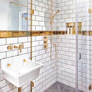 white metro tiles with gold metro tile border and gold shower and taps