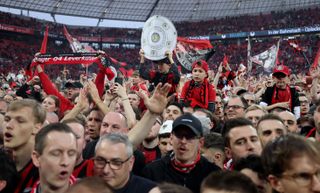 Bayer Leverkusen fans celebrate their club's Bundesliga title on the pitch after victory over Werder Bremen in April 2024.