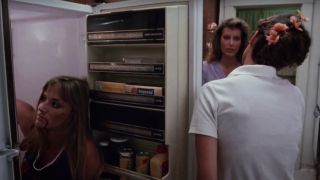 Two characters are oblivious to the fact that their friend's corpse is in the refrigerator in The Slumber Party Massacre