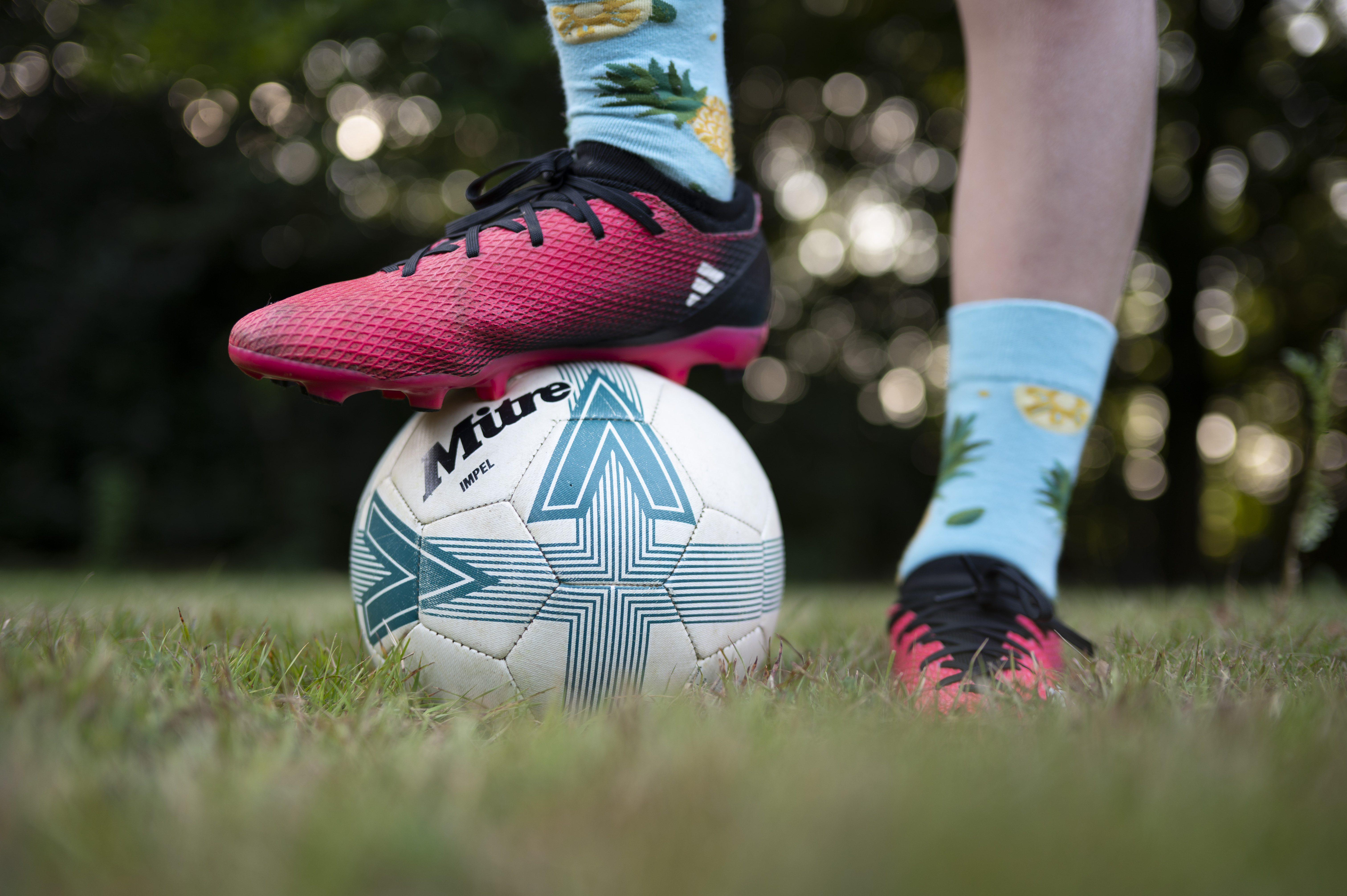 Closeup of a footballer's feet, with one foot standing on top of a ball