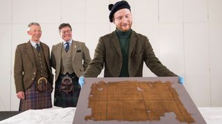 Peter MacDonald, head of research and collections and John McLeish, chair of The Scottish Tartans Authority and James Wylie, an assistant curator at V&A Dundee, examine the faded tartan.