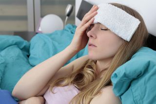 A woman lying down with a flannel on her forehead