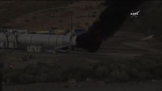 A robotic arm applies an extinguishing fluid to the rocket booster engine following a two minute test fire on June 28, 2016.