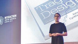 Generate speaker Cynthia Savard Saucier on stage with her book, Tragic Design, in the background 