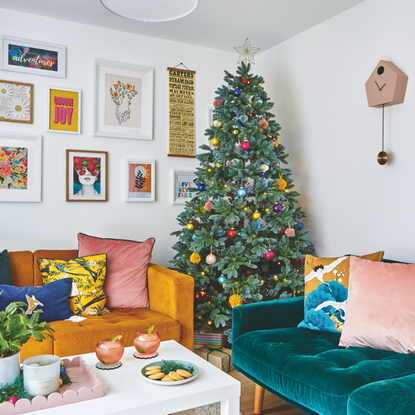 Christmas trees with bright colourful baubles in a colourful living room with a gallery wall.