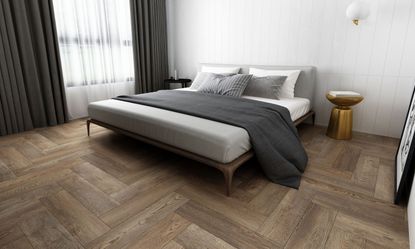 Gray LVT flooring in herringbone wood imitation design in modern bedroom with gray bedding