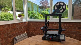 AnyCubic Kobra 3D printer surrounded by a garden