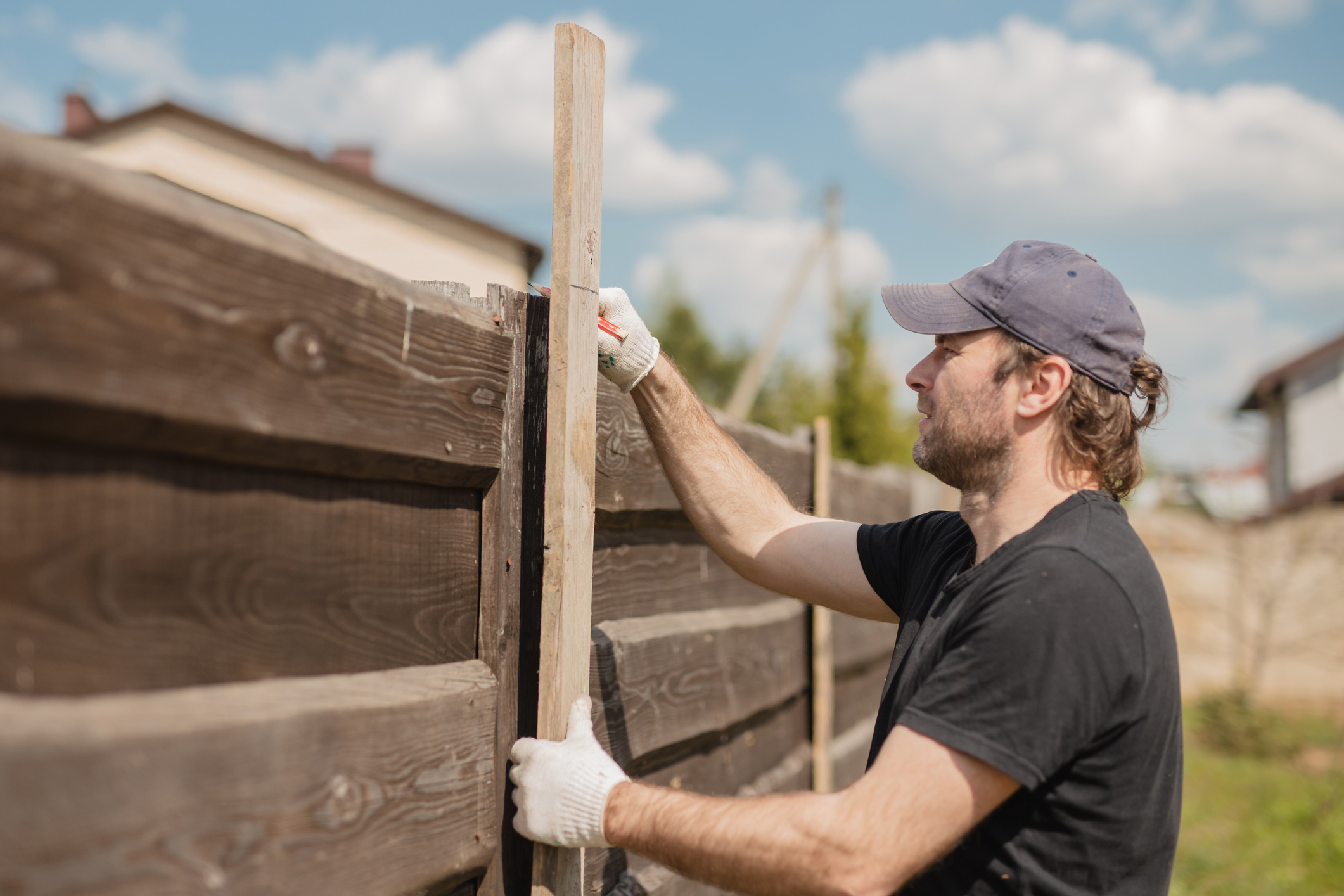 A man repairing a portion of his fence.