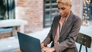 Woman using laptop on desk in office courtyard - best UI design tools