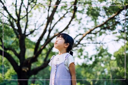 A young girl stood outside with her eyes closed