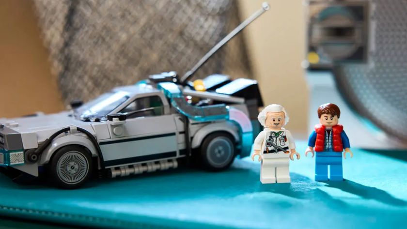 Lego Doc and Marty minifigures standing on a blue surface in front of the DeLorean car kit