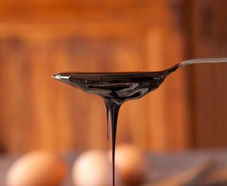 Blackstrap molasses drizzling from a spoon.