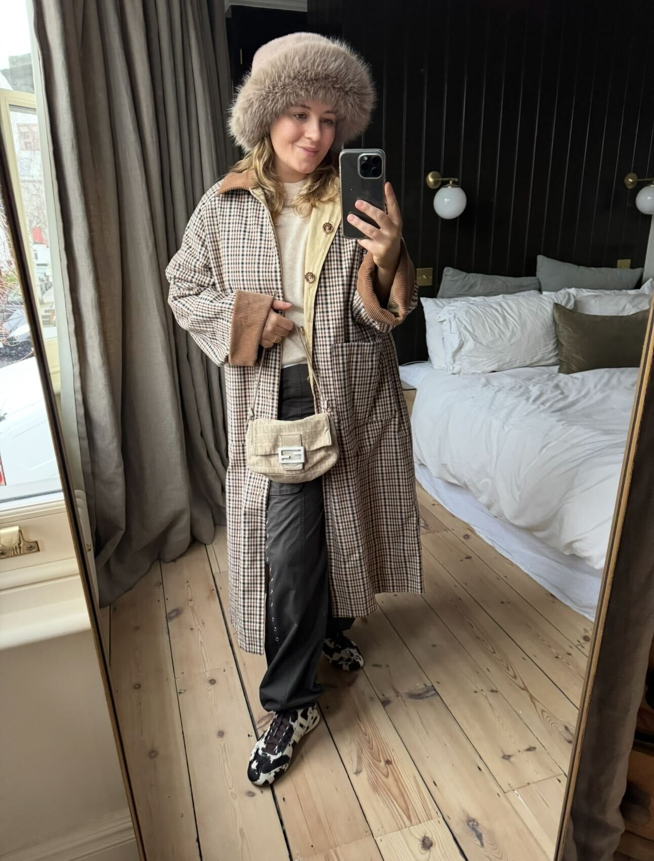 Rebecca Rhys-Evans takes a mirror selfie in check coat and cow-print adidas trainers.