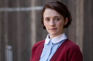 Barbara Gilbert (Charlotte Ritchie) stands outside Nonnatus House in her light-blue midwife's uniform with a red cardigan over the top