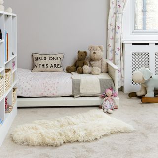 bedroom with white wall white flooring teddy bear on bed with cushion
