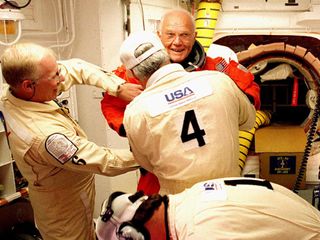In the launch pad's White Room, STS-95 Payload Specialist John H. Glenn Jr., U.S. Senator from Ohio, has his flight suit checked by closeout crew members before climbing into space shuttle Discovery for his second flight into space, which came 36 years af