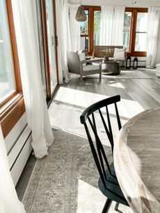 Grey laminate floor in sunroom with round dining room table and wooden chair