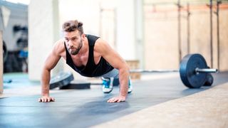 how to gain muscle: Image shows man doing press ups in gym