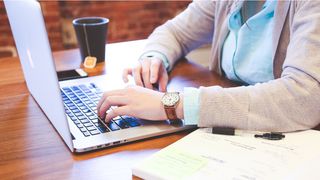  Woman working on laptop, with coffee cup 