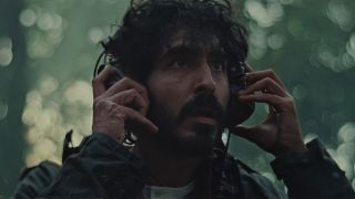 dev patel looks scared and holds onto headphones in a still from the movie rabbit trap