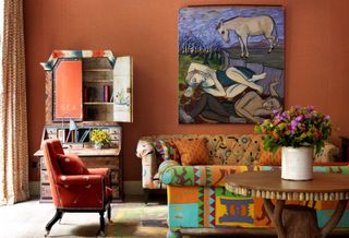 The English eccentric Ham Yard Hotel's drawing room features a vibrant color palette, upholstered furniture boasting eye-catching prints, a huge painting, and wooden furniture.