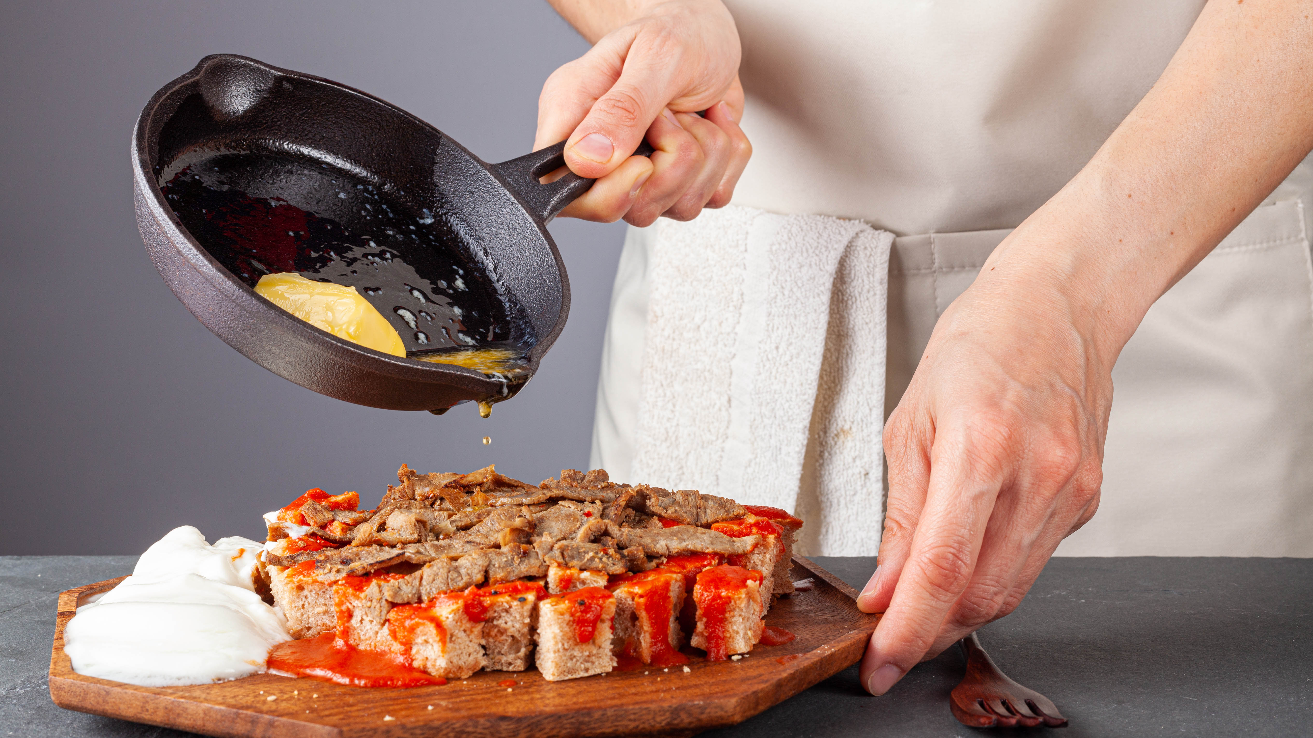 Чугунная сковорода выливает сок на ингредиенты на деревянном сервировочном блюде.