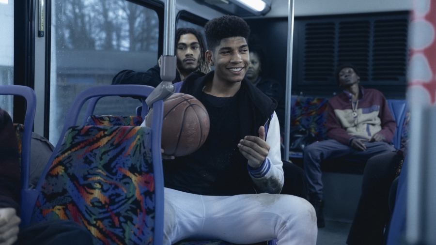 Bryce Clyde Jenkins as Terrell sitting on a bus and holding a basketball.