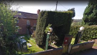 A brick building with two petrol filling stations in the front garden
