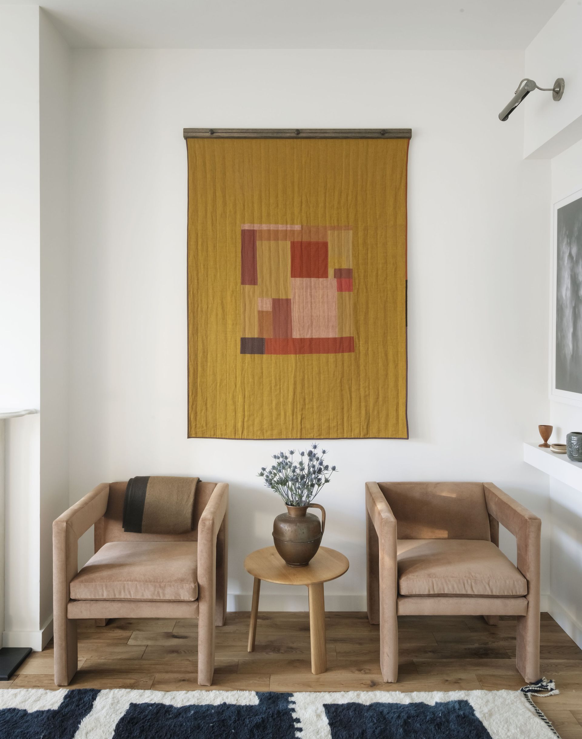 living room with white walls, two minimalist velvet chairs and artwork