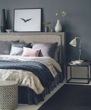 Grey bedroom, large double bed, faux fur throw, cushions, headboard display, bedside table.
