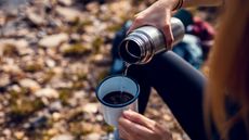 Young woman having a cup of coffee while taking a break from hiking