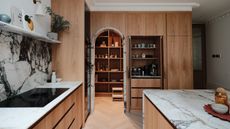 A marble and oak kitchen. In this kitchen is an arched door leading into a large pantry.