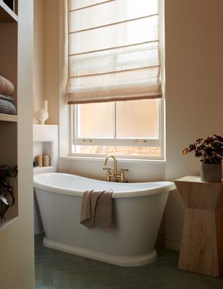 Beige bathroom with large window and freestanding bath
