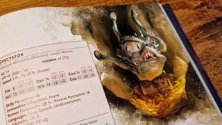 The Monster Manual Spectator artwork and stat block, lying against a wooden surface